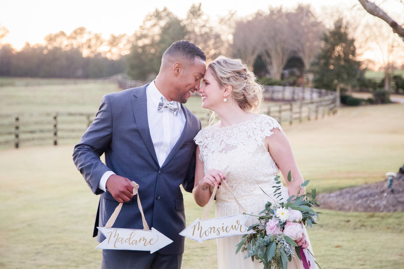 An interracial couple holds signs at their wedding at the Venue at Murphy Lane by Jennifer Marie Studios, best Atlanta wedding photographer.