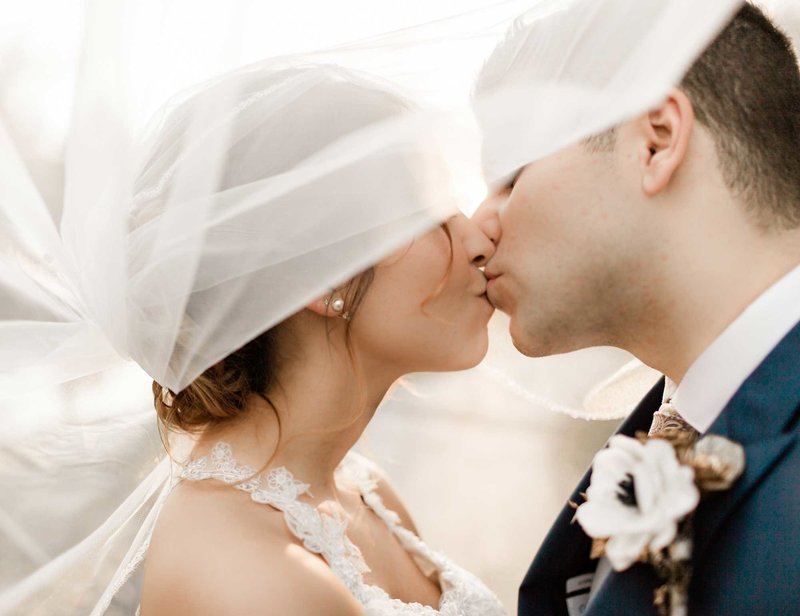 bride and groom under the veil kissing for naples wedding photos
