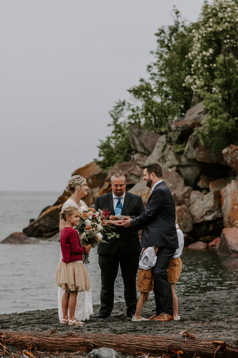 Couple having their elopement ceremony on the black sand of black beach mn with their kids.