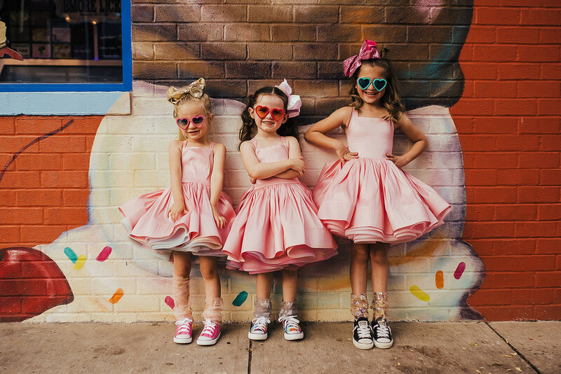 three girls in pink dresses smiling standing in front of Bmore Licks in Federal Hill Baltimore Maryland