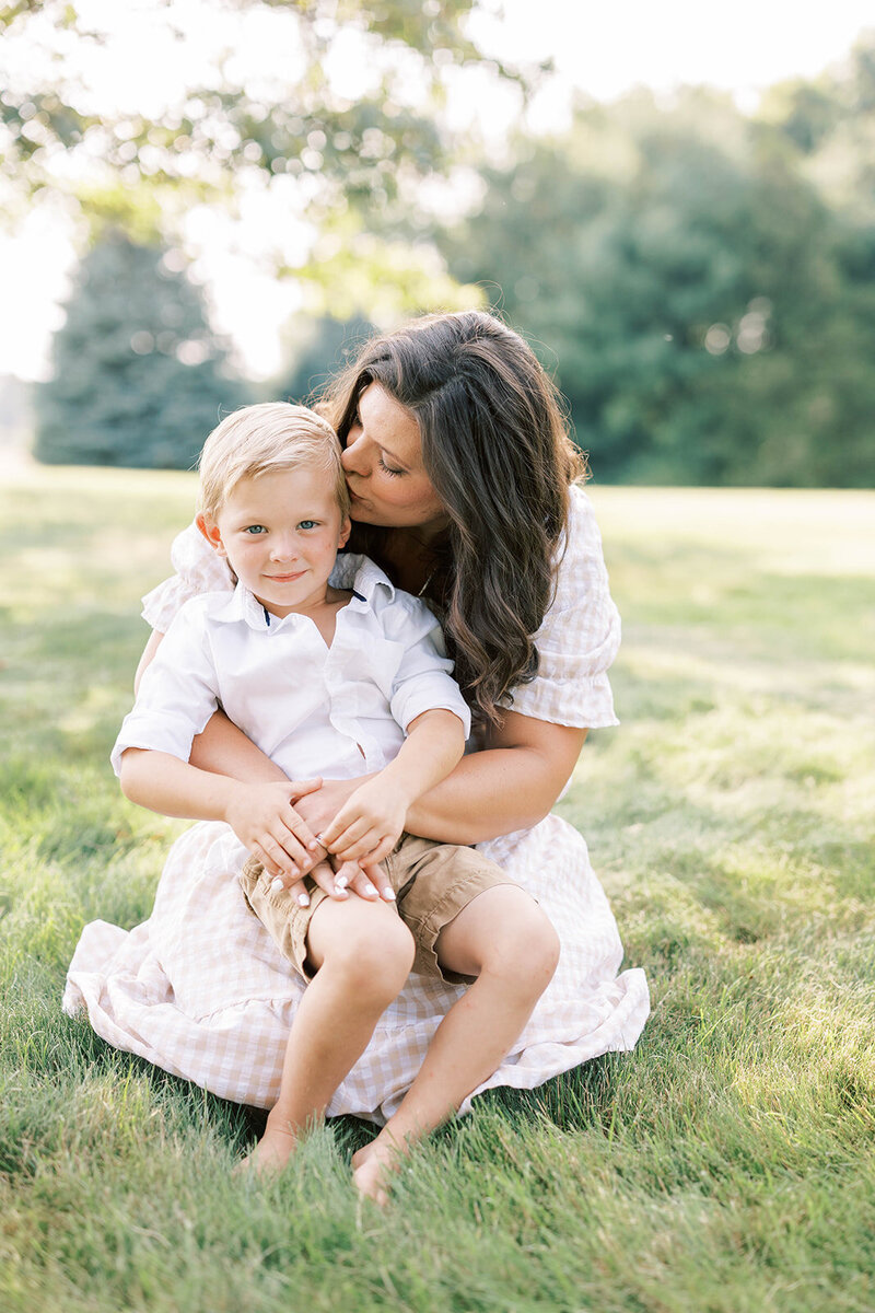 Mom kisses son on the cheek as he smiles in summer Mechanicsburg field.