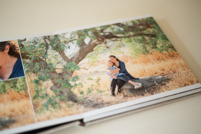 Luxury photo album showing and mom holding her young daughter in the California golden hills