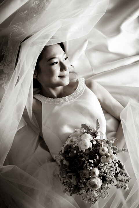 Bride lying on the bed with a wedding bouquet in her hand
