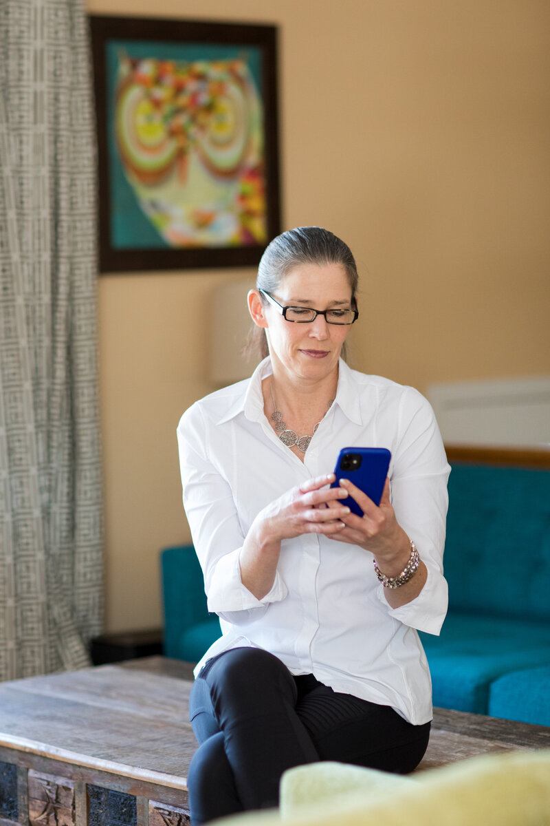 woman sitting on a coffee table looking at her phone
