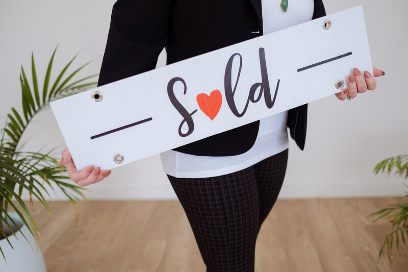 Stock photo of a realtor holding a "sold" sign