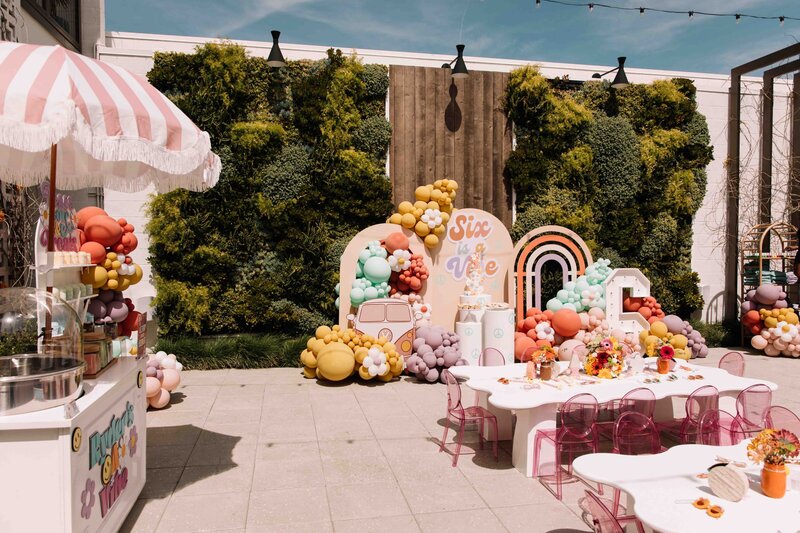 Set against Hart and Main's Garden Wall stand Tables with pink table cloths 