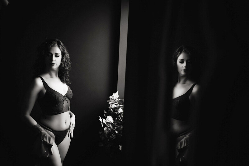 Black and white portrait of woman in lingerie posing in a mirror