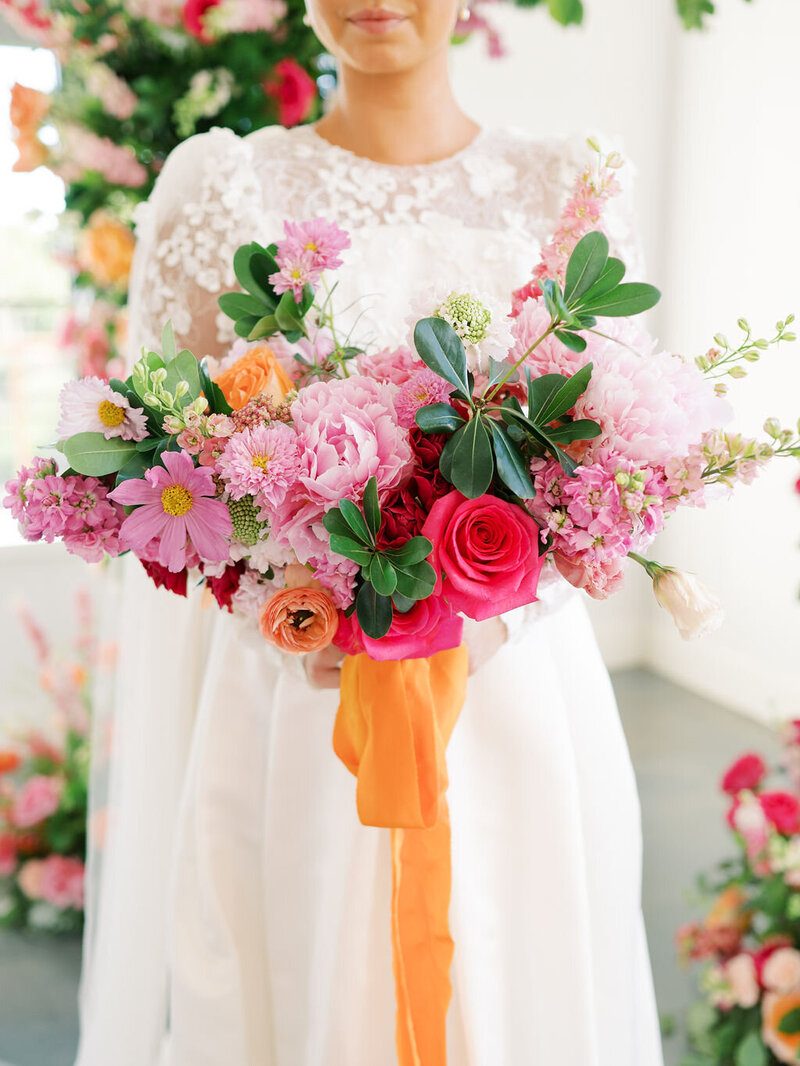 Bride holds a colorful pink and orange wedding bouquet