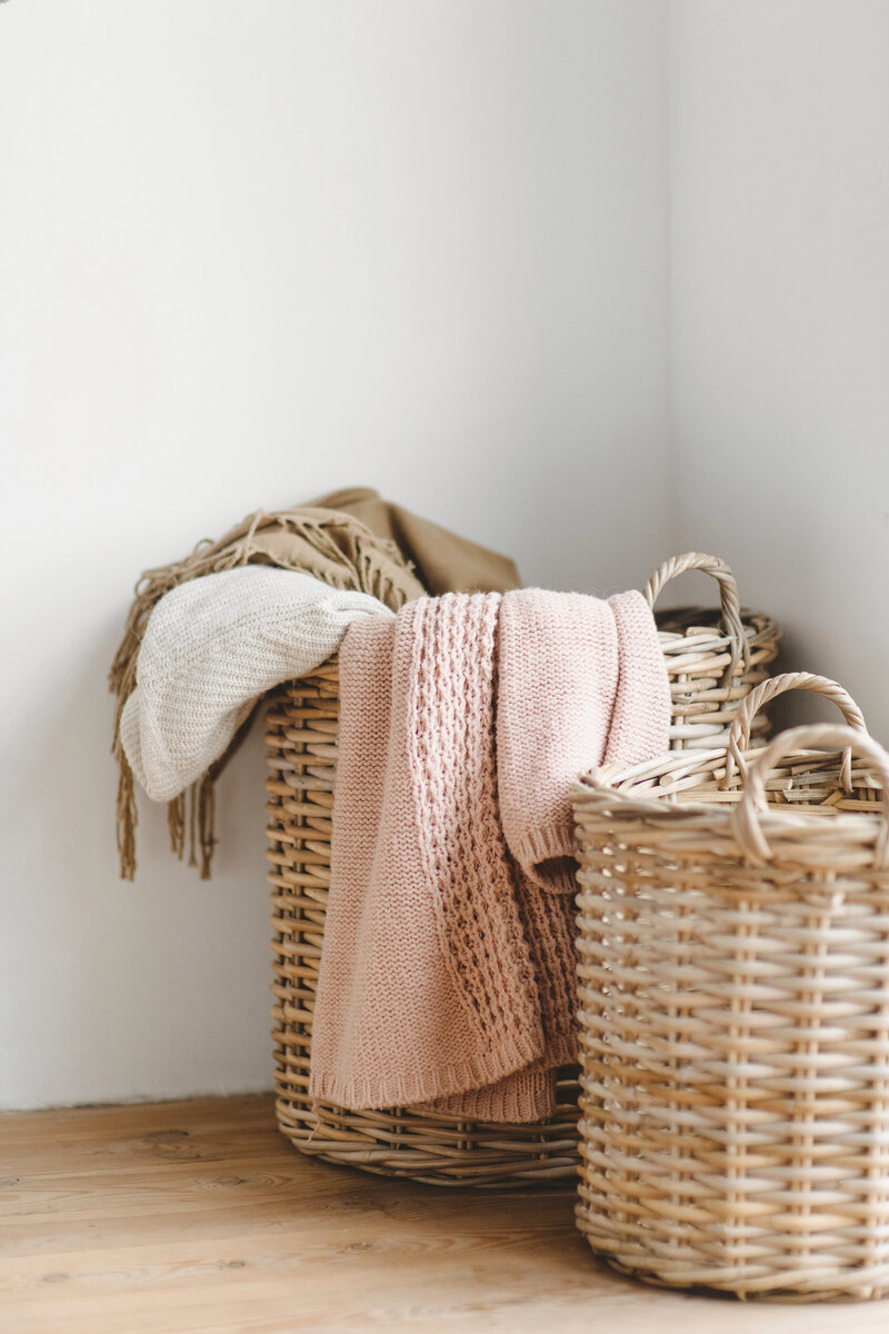 brown wicker laundry baskets, pink and tan afghans, sitting on wood floor