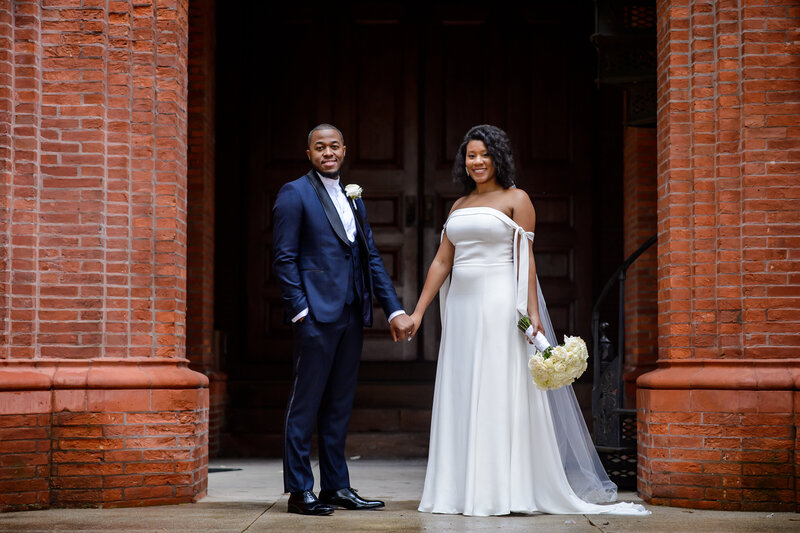 bride and groom holding hands outside wedding chapel at Hampton University.