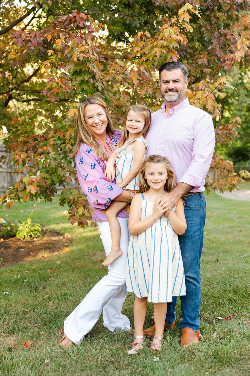 A family of four posing for a photo in front of a tree at a family photo session in Lexington KY.