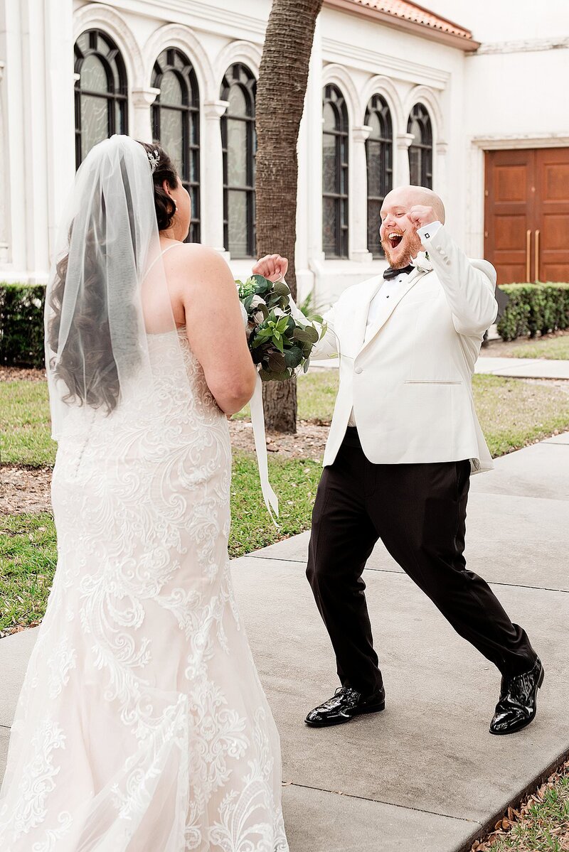 Groom giving his bride an epic and fun reaction during their first look, he's wearing a classic black and white tux with a bowtie