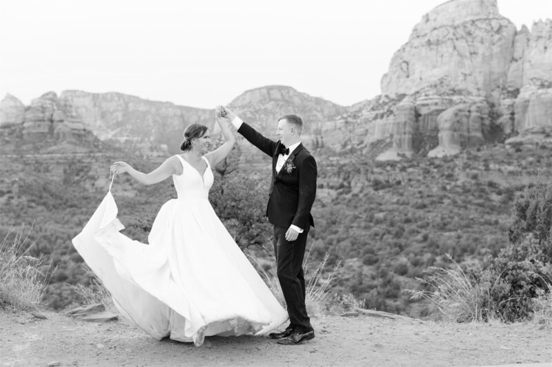A bride twirls in her wedding gown as her groom holds her hand against a scenic mountain backdrop, capturing the romance of a destination wedding by Socially Significant Events.