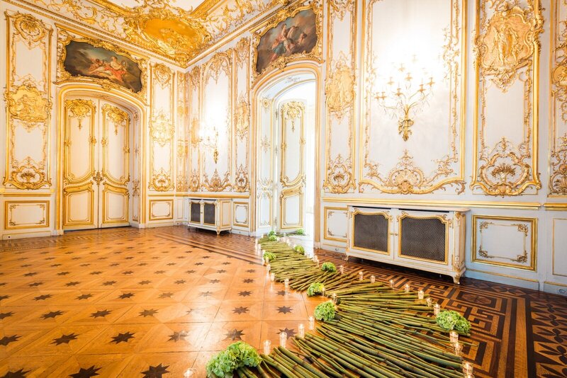 Historic room with ornate gold decor and trail of bamboo on floor