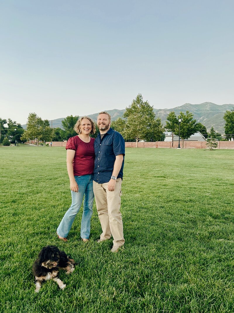 Owners of Cornerstone Dog Training in a field with a dog