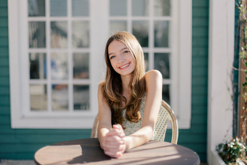 A young girl smiling while sitting at a table on a coffee shop patio in Galveston