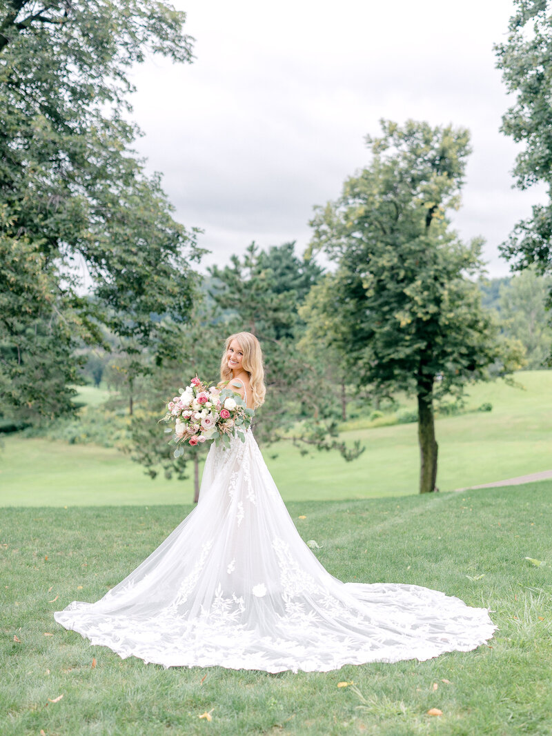 Outdoor portrait of bride with her train spread out behind her and holding her bouquet
