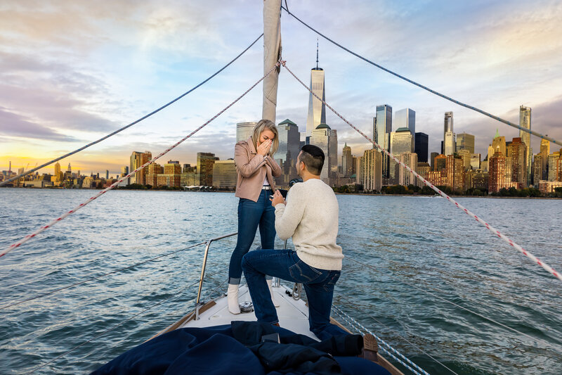 Man proposing to a woman on a boat with New York City in the background