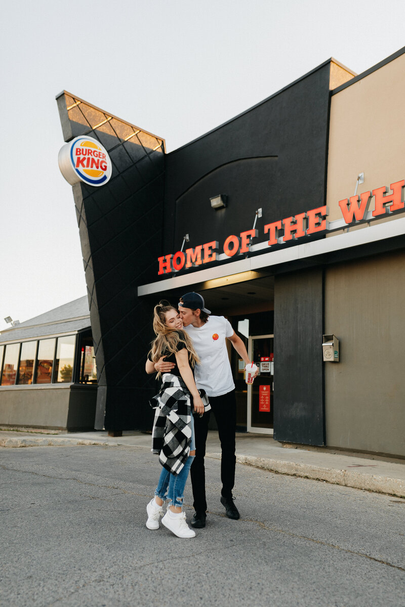man and woman arm in arm laughing in front of burger king