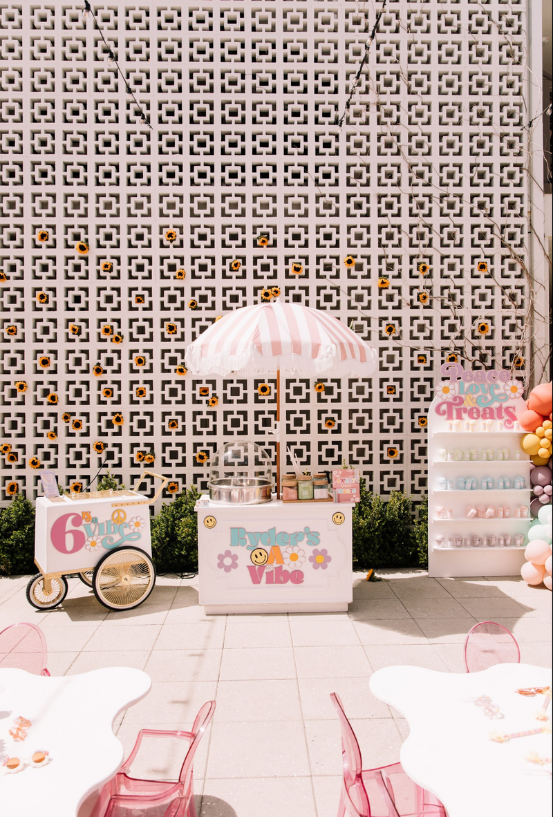 Birthday decorations--an ice cream cart, lemonade stand and giftbag shelves--for a six year old sit in front of Hart and Main's Breezeblock wall
