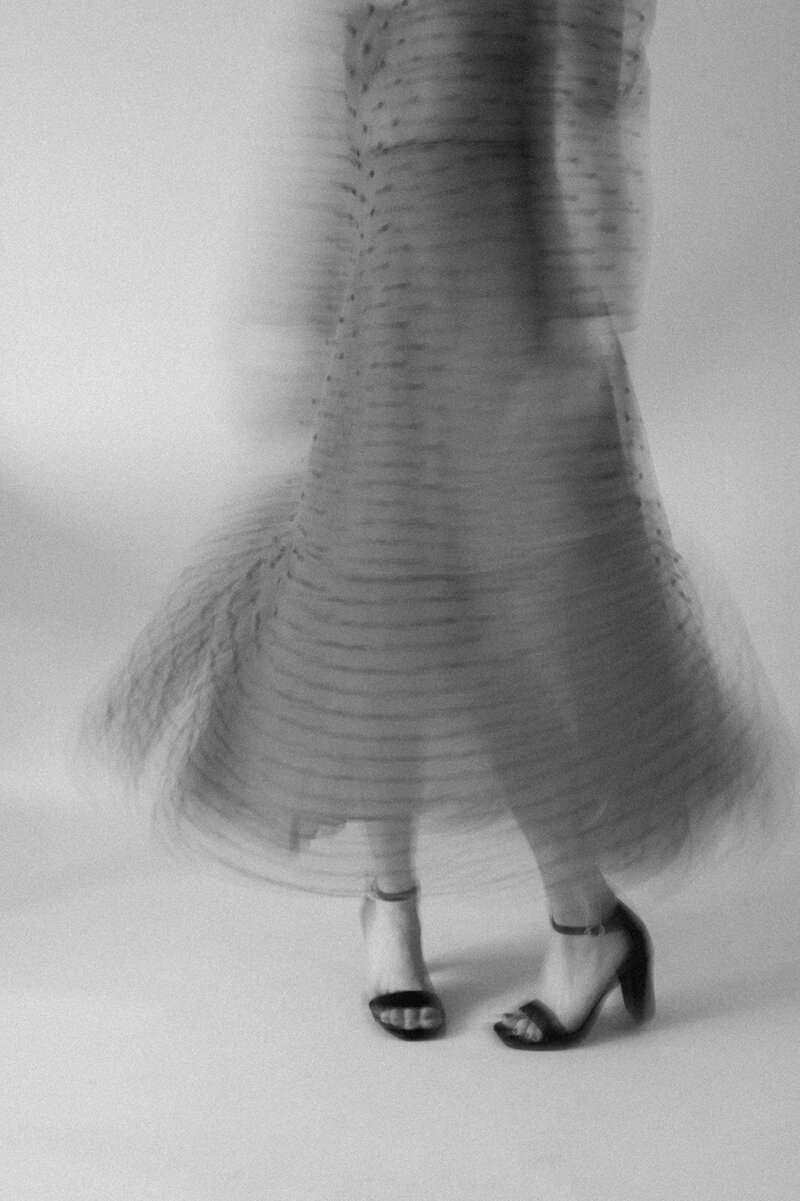 Black and white blurred image of a woman twirling her polka dot dress