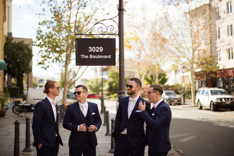 Groom and Groomsmen standing at the sidewalk wearing their suits and shades