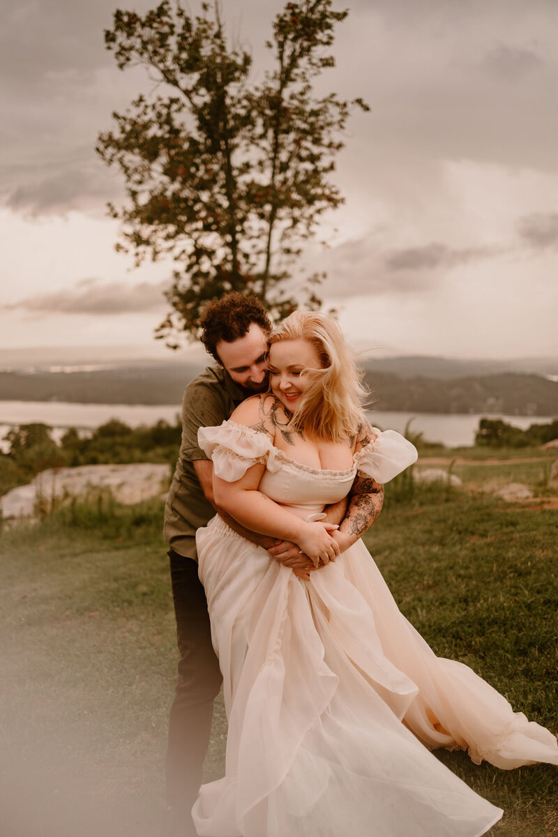 man and woman embracing on grassing cliffside during wedding day in gloomy weather