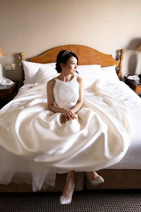 Beautiful Bride sitting on the bed wearing her wedding dress
