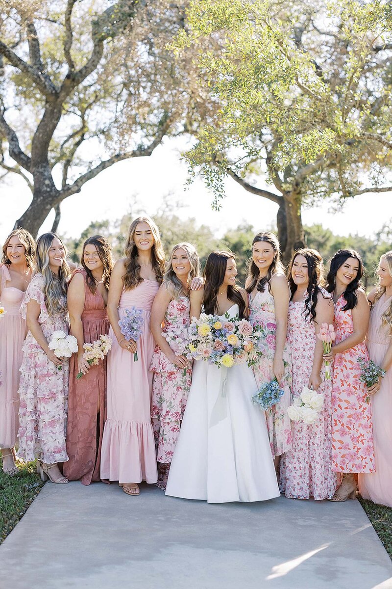 Bride with bridesmaids in mismatched floral pink dresses