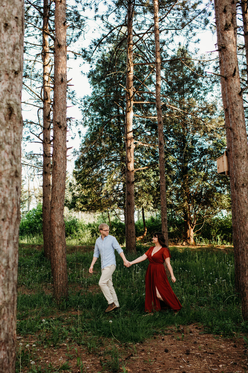 Man and woman holding hands and walking through a forest