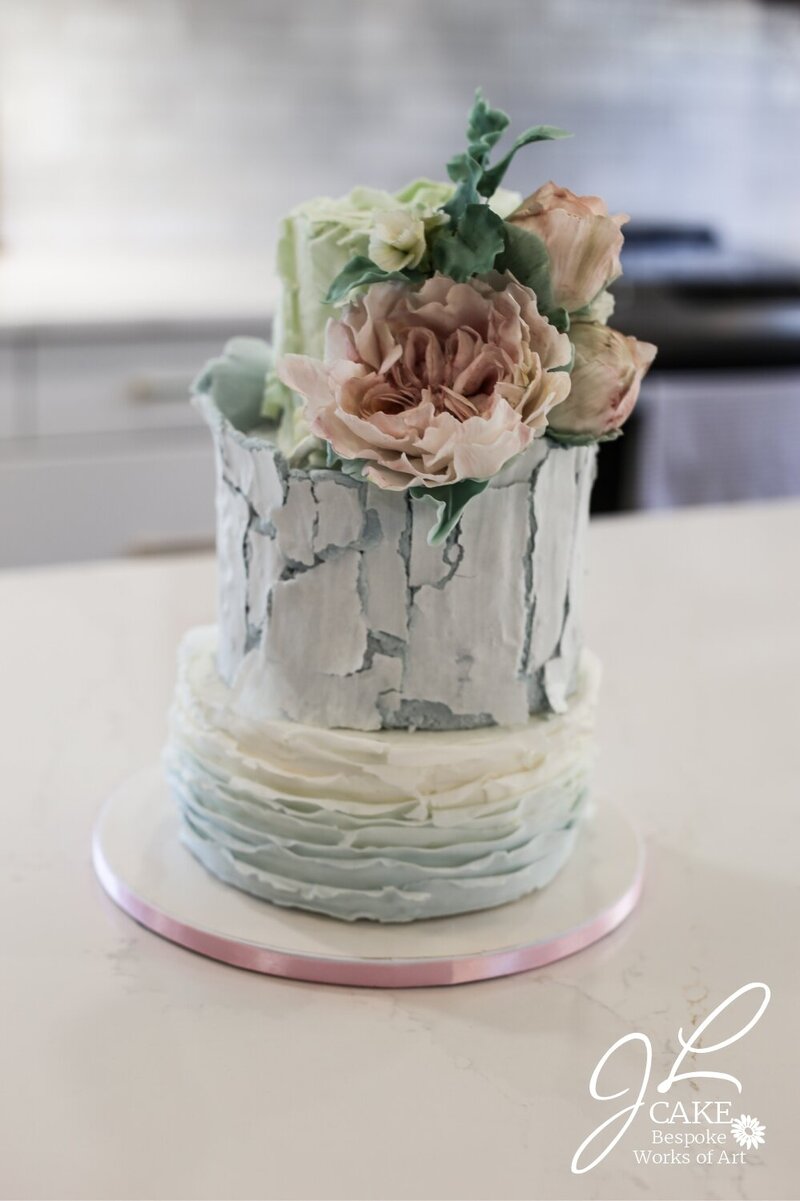 rustic cake with fondant ruffles, crackling bark, and green with white roses and  pale pink peony and greenery.