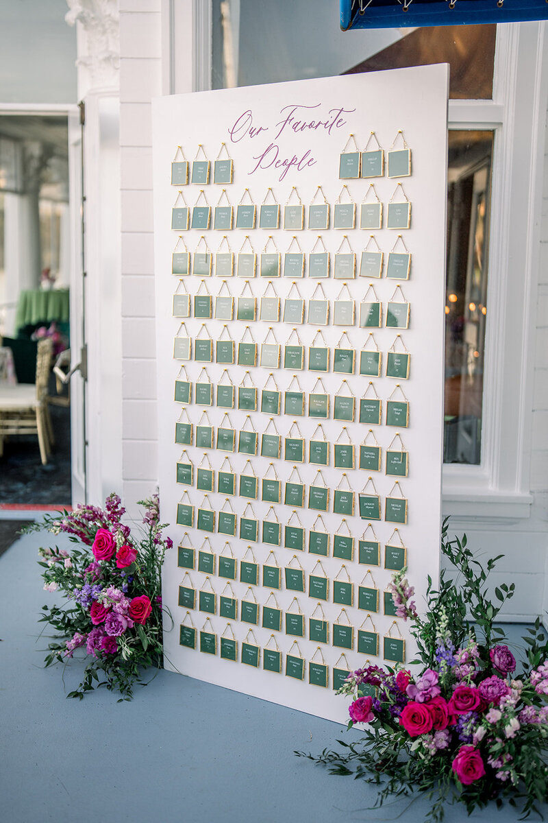Green and white escort card display surrounded by vibrant florals at a Bay Area wedding photographed by a California editorial wedding photographer.