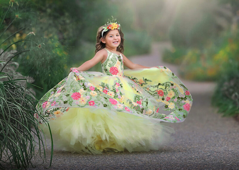 Young lad twirling in orgeous yellow dress at her denver childrens photography session