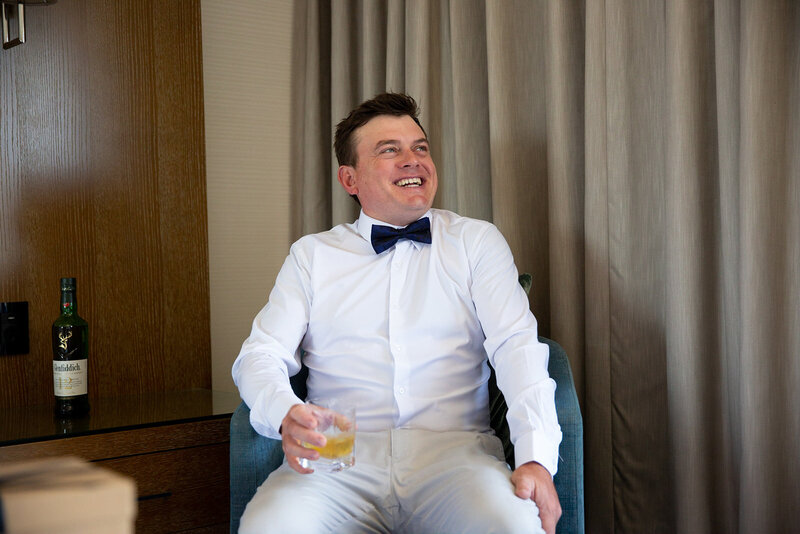 Happy groom sits while holding a glass of champagne
