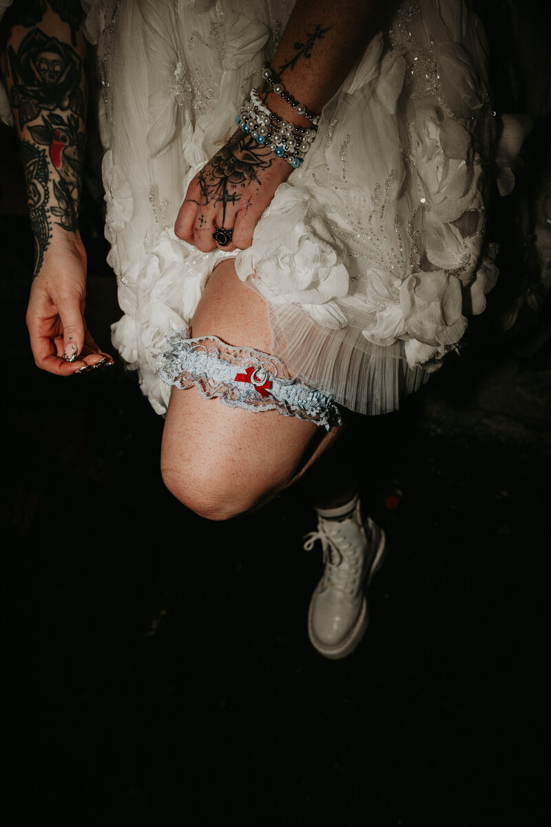 A blue garter with a lucky horse shoes on a tattooed brides leg.