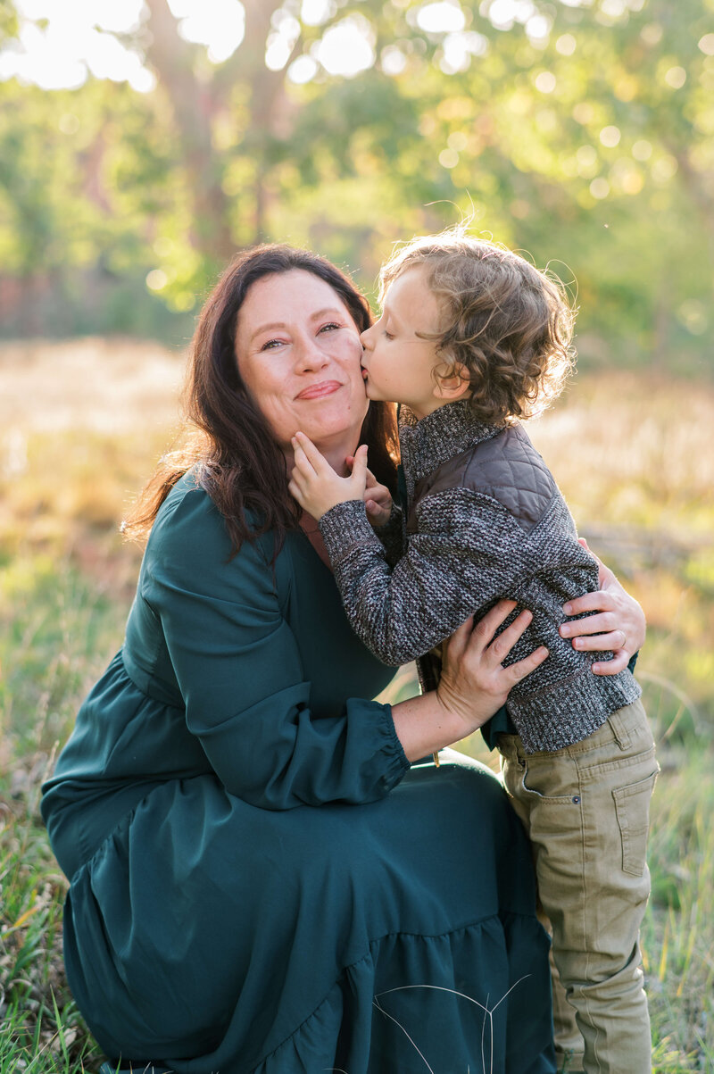 Little boy kisses his mom on the cheek during a session with DMV family photographer