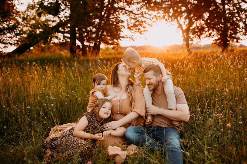 Family of five sitting in a southeastern wisconsin field at sunset.