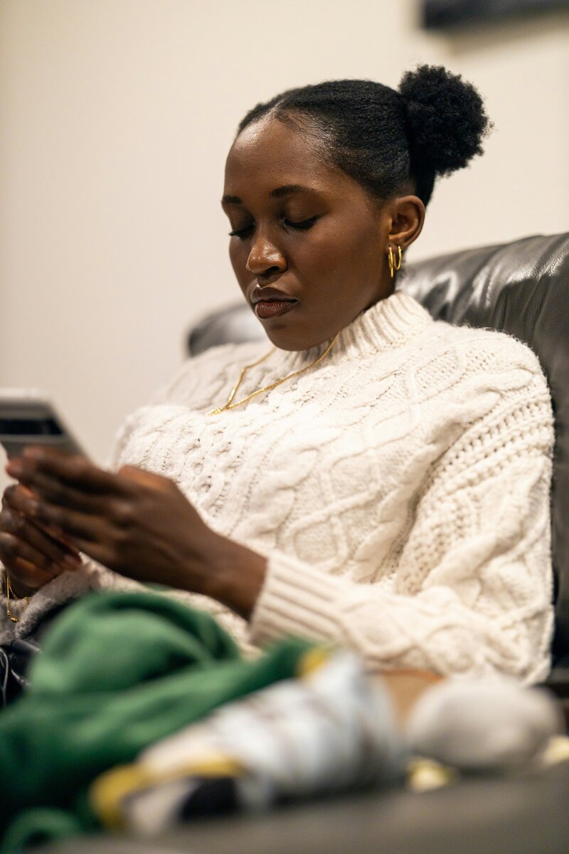 Black woman looking at phone wearing white