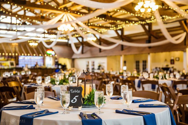 Inside the Great Hall at Church Ranch Event Center with tables decorated with lanterns and blue napkins