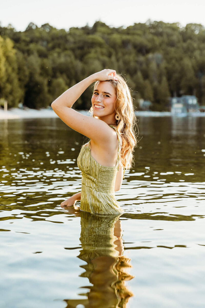 senior in a green dress posing in the water for senior session
