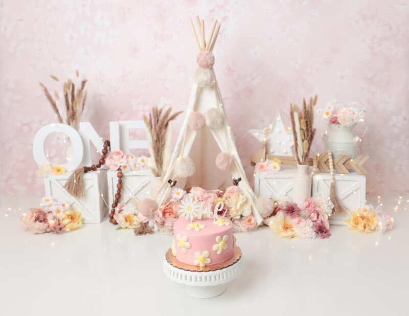 Beautifully styled boho cake smash scene with a decorated cake and playful props in Rochester, NY.