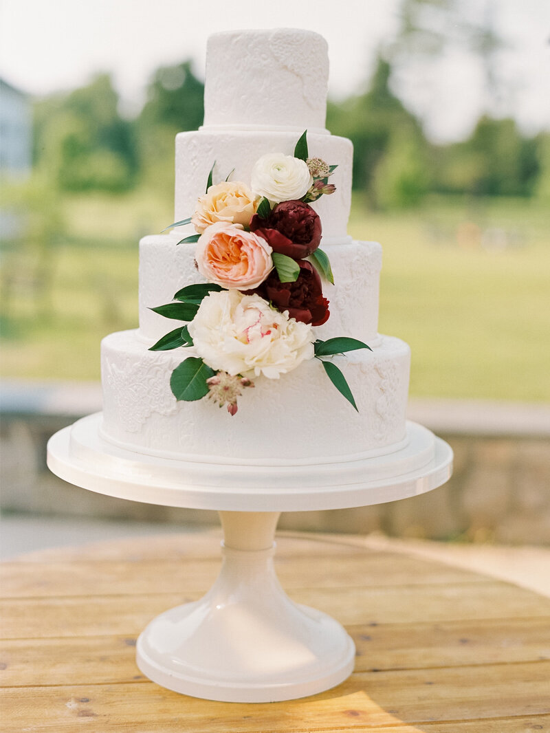 Simple white wedding cake with florals and lace design