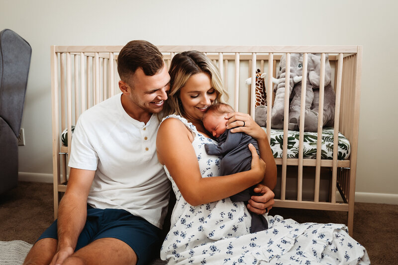 Couple holding baby boy in front of crib