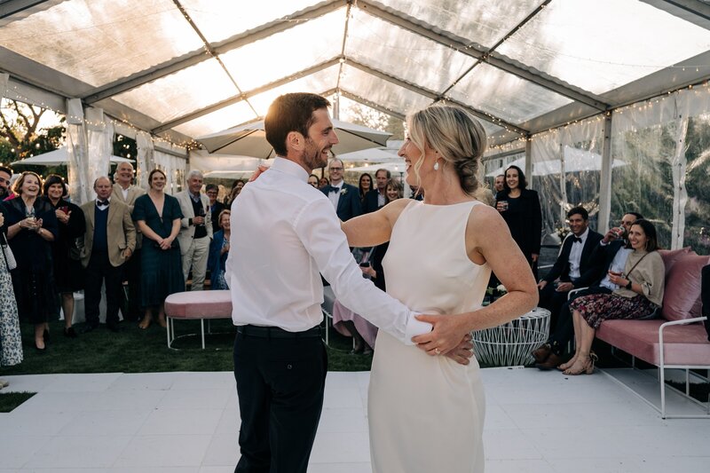 newly married couple dance in clear marquee on white dance floor with pink velvet furniture from little hire company