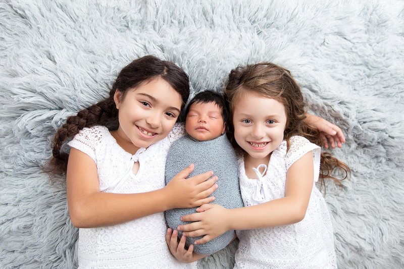 Sisters with baby brother blue