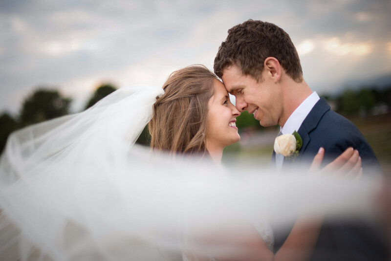 Wedding Photographer, A bride and groom with their heads pressed together smiling at each other outside