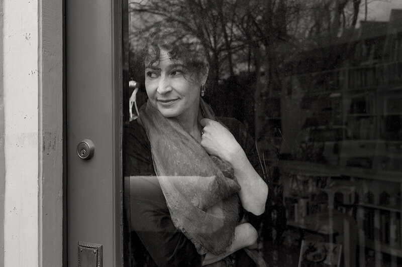 Female musician portrait black and white Brenna MacCrimmon looking through glass door while leaning against it