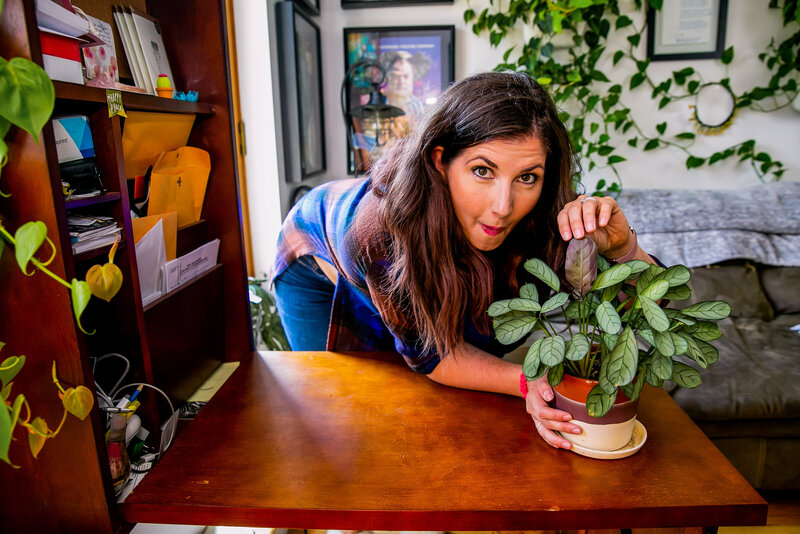 Maria, host of Bloom & Grow Radio, admires a favorite plant in her apartment