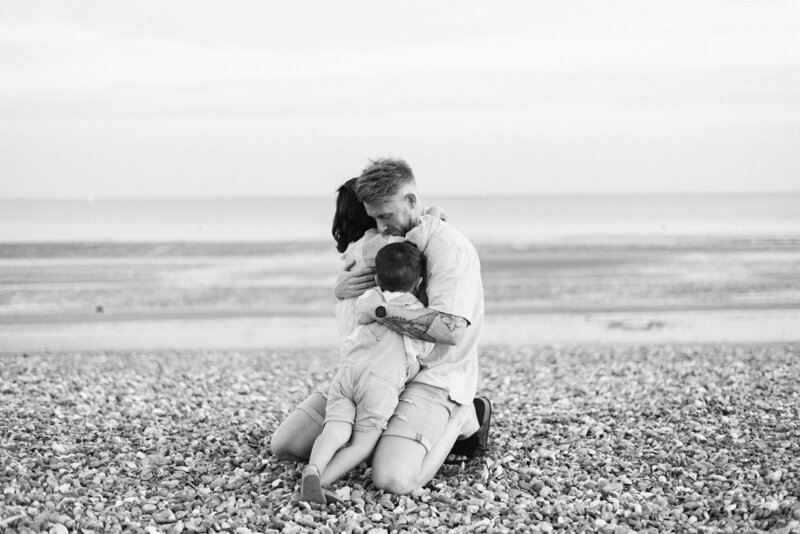 Dad hugging his two children on a beach in family photoshoot in Billingshurst