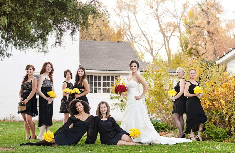 Bride with bridesmaids outside of white rustic farmhouses at Chatfield Farms Denver Botanic Gardens in Denver